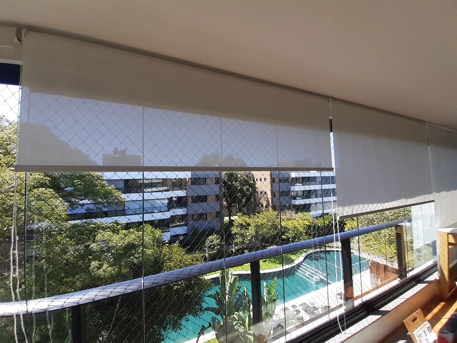 Persiana Rolô Screen em varanda com vista para piscina e prédios — projeto real LUME